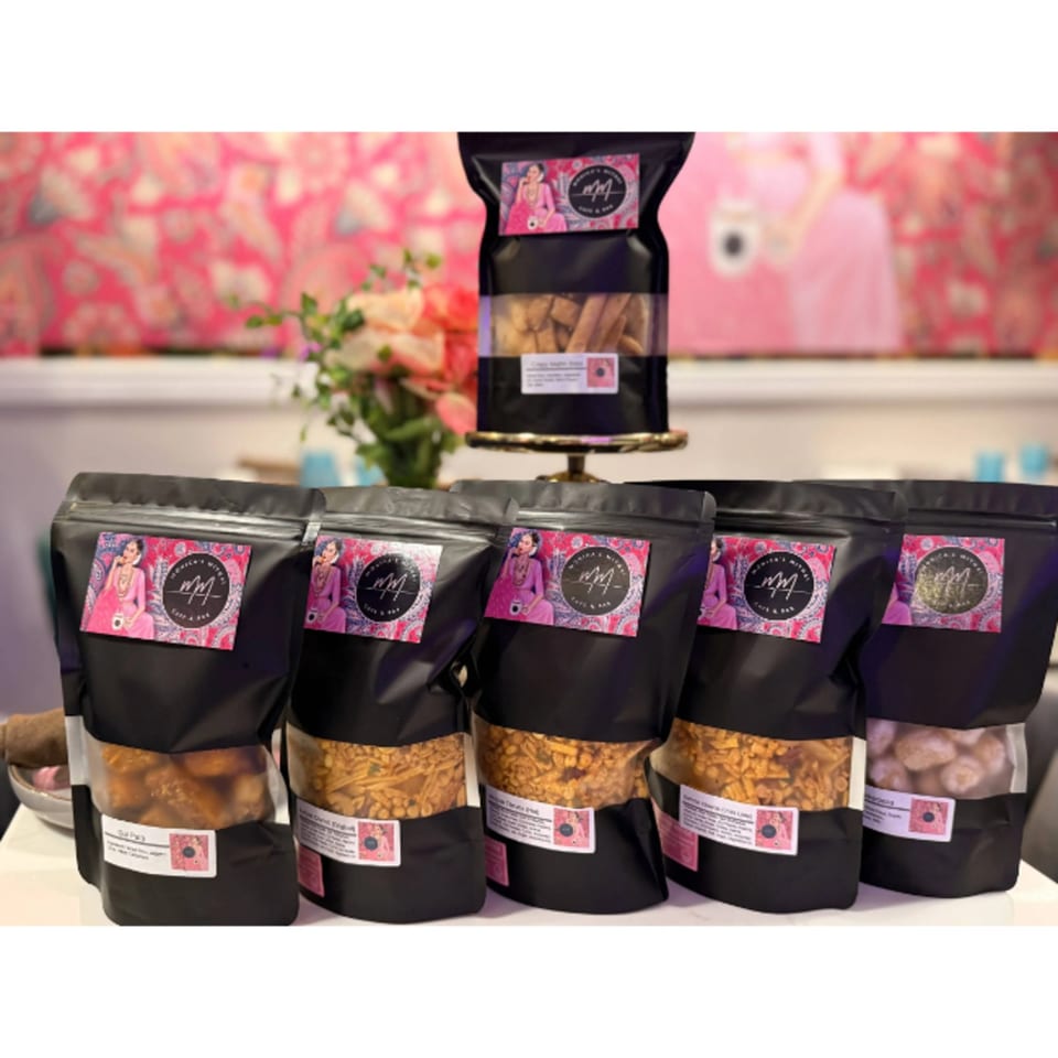 Monica's Mithai Cafe & Bar's branded bags of Indian snacks and sweets on display.