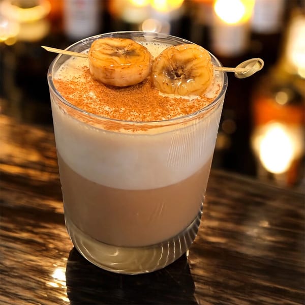 A layered Indian drink with cinnamon and caramelized banana slices on a skewer.