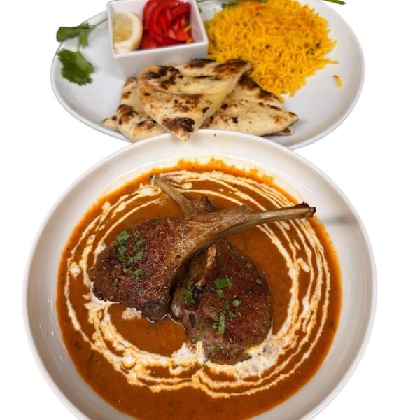 Indian lamb chops in curry sauce with naan bread, yellow rice, and pickled onions.