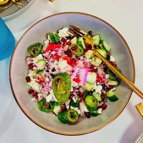 A vibrant Indian salad with cucumbers, red onions, feta, pomegranate seeds, and green chilies.